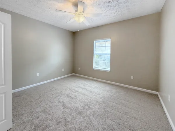 an empty room with a ceiling fan and a window