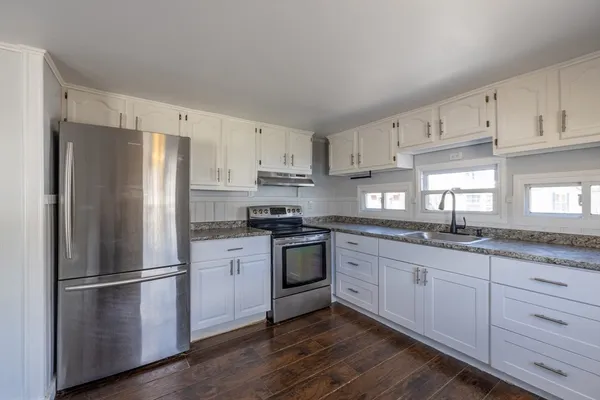 a kitchen with granite countertop stainless steel appliances a refrigerator a sink and cabinets