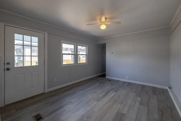 an empty room with wooden floor and windows
