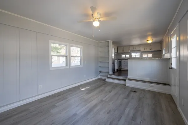 an empty room with wooden floor a ceiling fan and windows