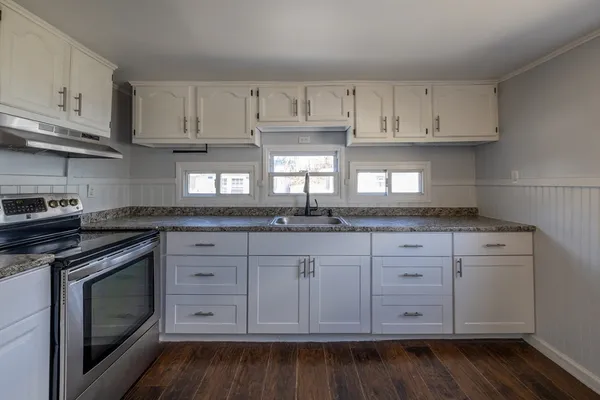 a kitchen with granite countertop white cabinets and stainless steel appliances