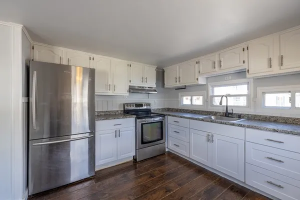 a kitchen with granite countertop stainless steel appliances a refrigerator a sink and cabinets