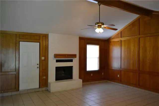 a view of an empty room with a fireplace cabinet and window