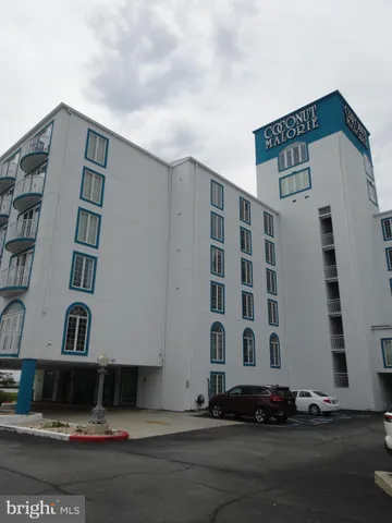 a front view of a building with garden and plants