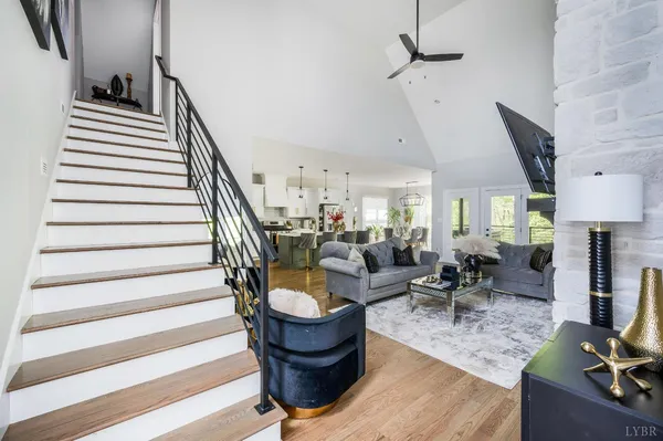 a living room with couches chairs and kitchen view with wooden floor