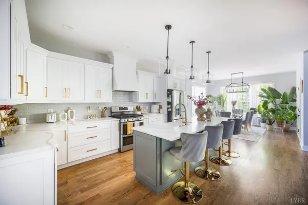 a room with stainless steel appliances kitchen island granite countertop a table chairs and a stove