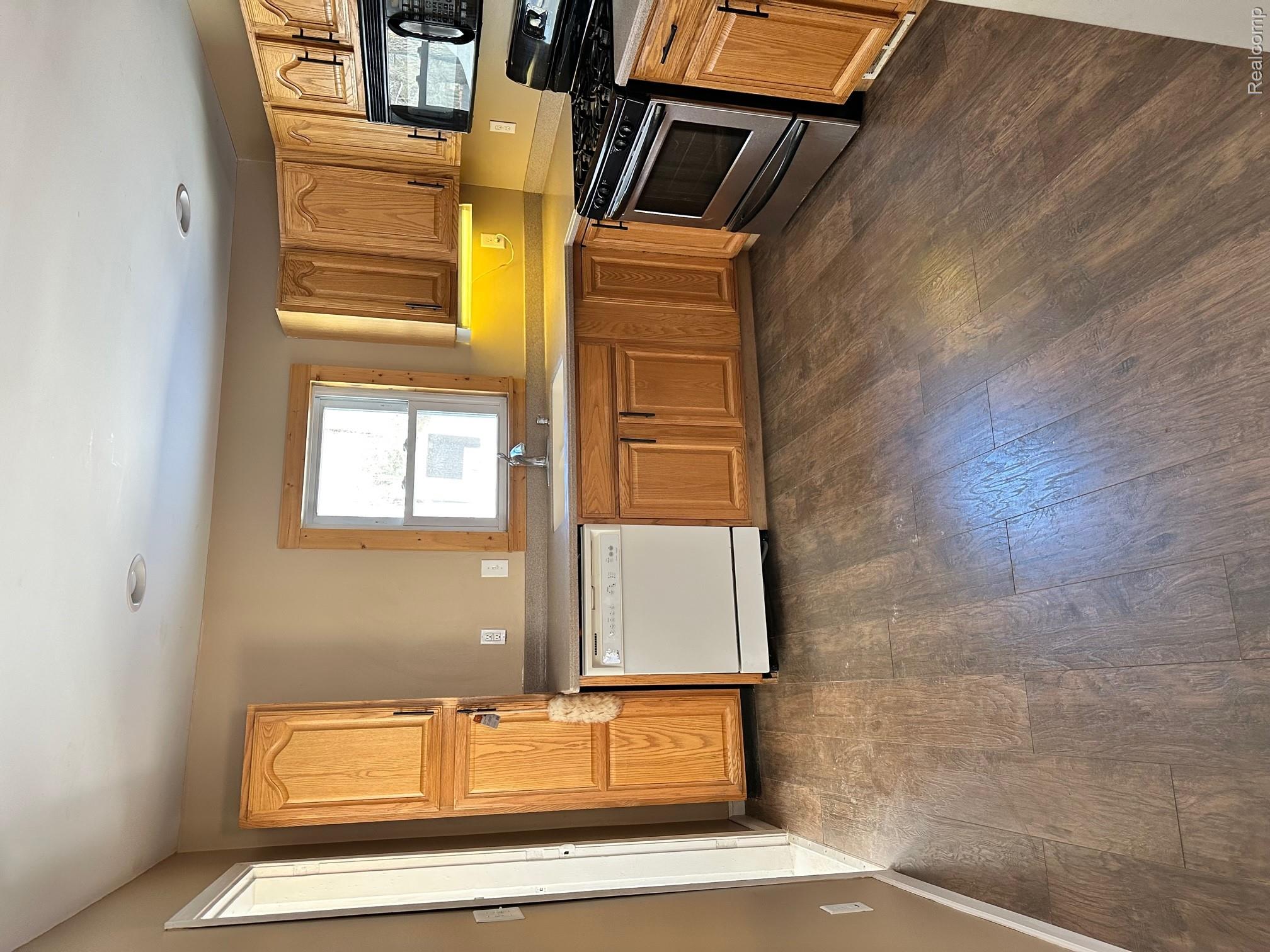 Wood-finish flooring, recessed lighting, wood cabinetry, built-in dishwasher, and a stainless steel oven/range