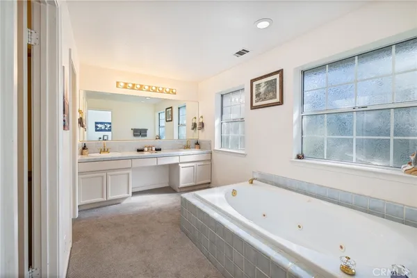 a bathroom with a bathtub a double vanity sink and a window