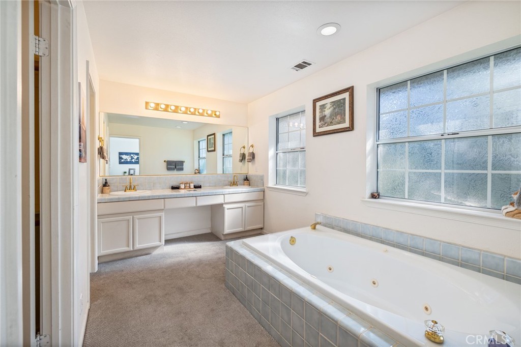 39301 Moonray Lane Oakhurst, CA 93644 - Photo 28 of 55 a bathroom with a bathtub a double vanity sink and a window