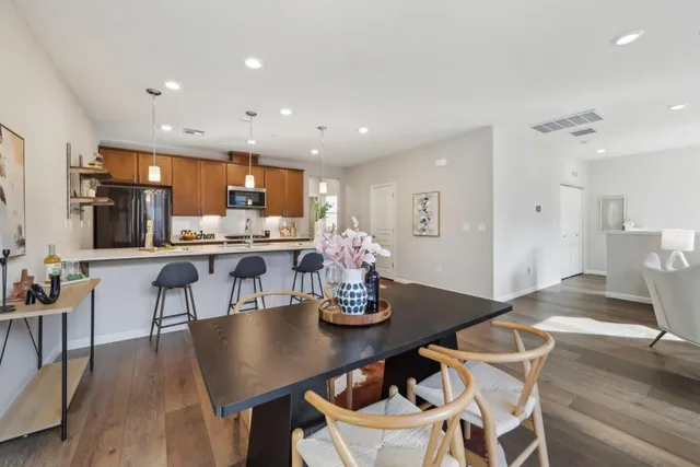 a kitchen with stainless steel appliances kitchen island granite countertop a dining table chairs and stove top oven with wooden floor