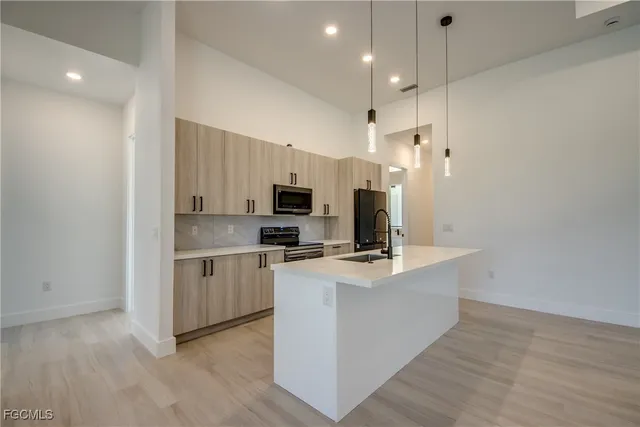 a kitchen with kitchen island a sink a stove a refrigerator and white cabinets