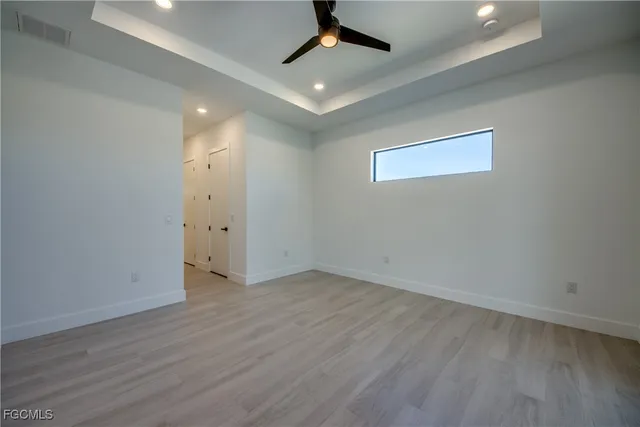 an empty room with wooden floor and a ceiling fan