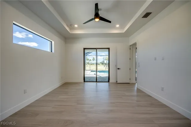 a view of an empty room with window and wooden floor