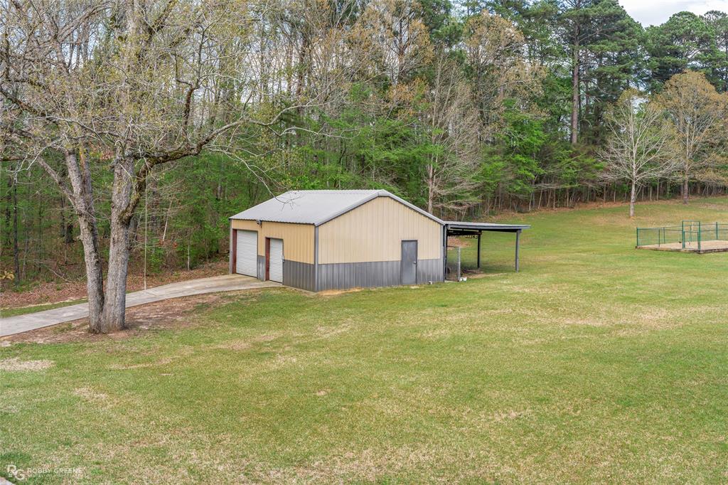 195 Tanglewood Road Homer, LA 71040 - Photo 33 of 37 a backyard of a house with large trees and wooden fence