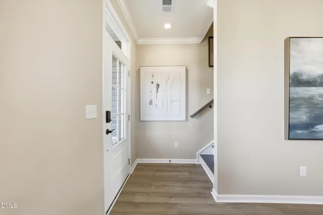 a view of a hallway with wooden floor and a bathroom