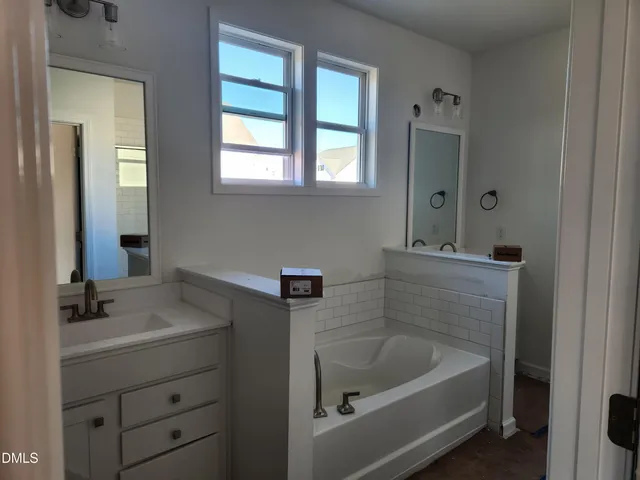 a bathroom with a tub sink and mirror