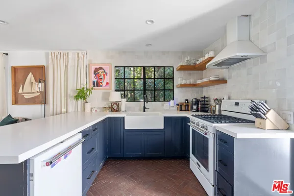 a kitchen with a sink cabinets a stove and a window
