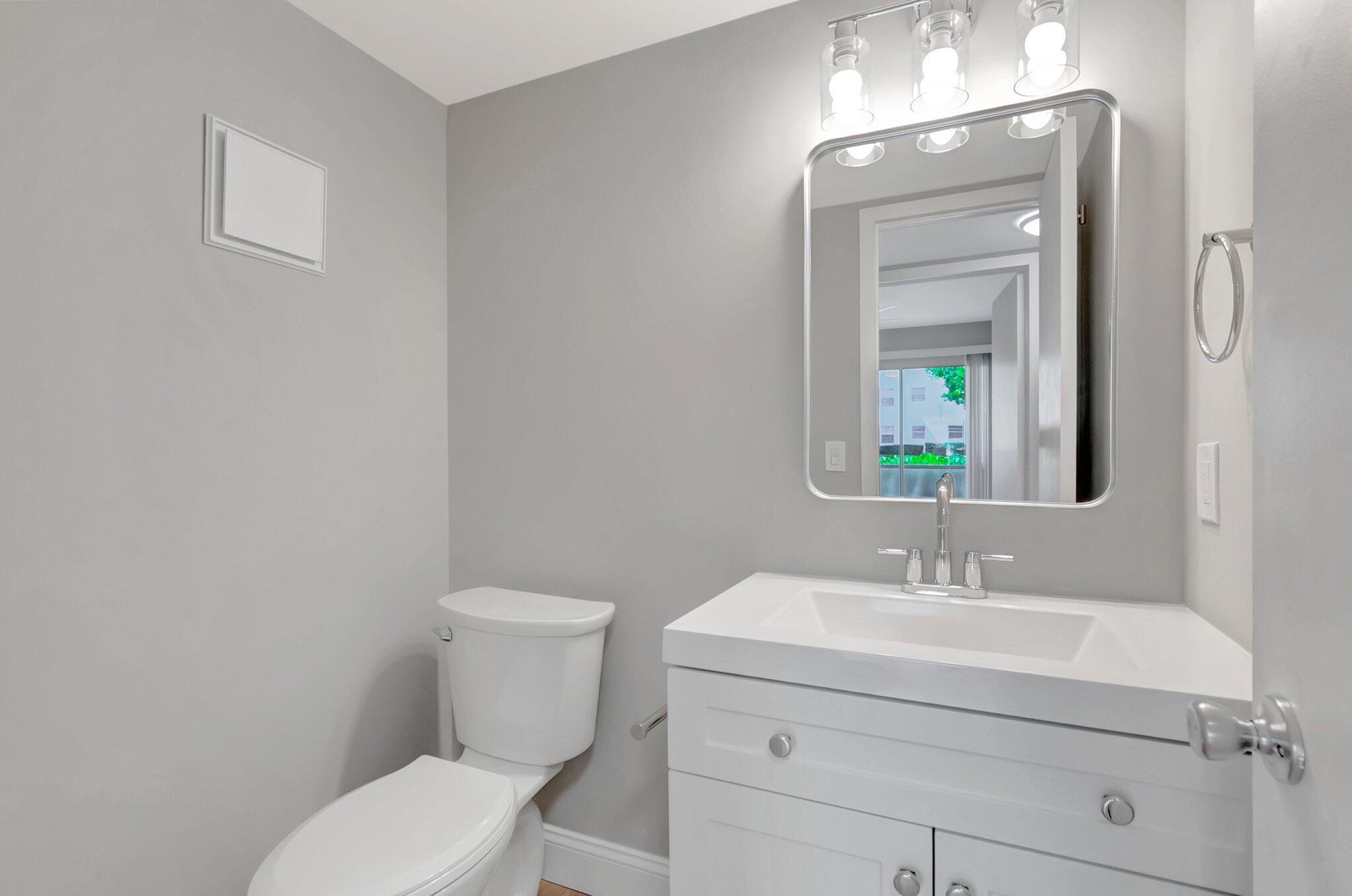 296 Fanshaw H Boca Raton, FL 33434 - Photo 14 of 59 a bathroom with a toilet a sink and mirror