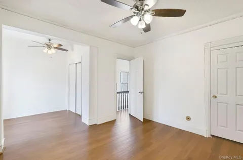 an empty room with wooden floor fan and windows