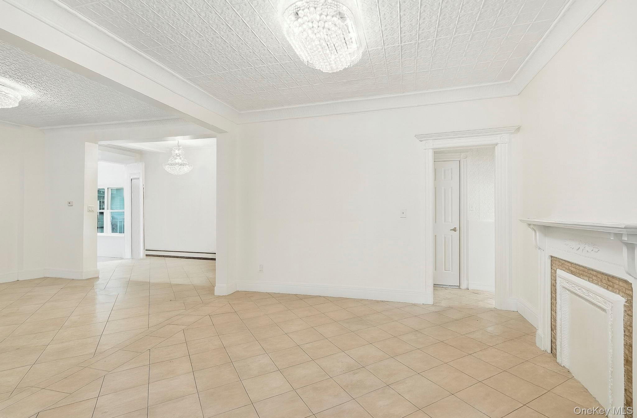 3340 Perry Avenue Bronx, NY 10467 - Photo 8 of 42 an empty room with a fireplace and a chandelier fan