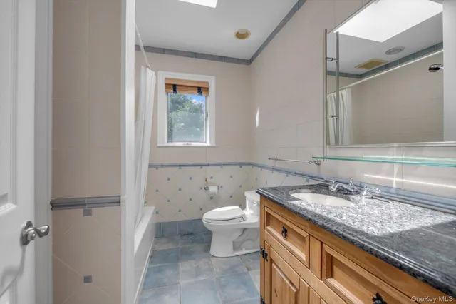 a bathroom with a granite countertop sink a toilet and a mirror