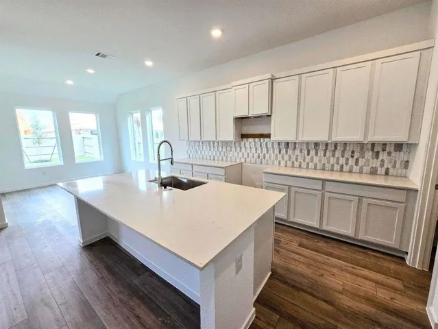 a kitchen with a sink a stove cabinets and wooden floor