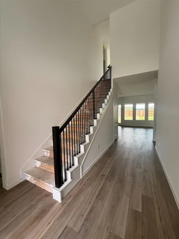 a view of a hallway with wooden floor and staircase