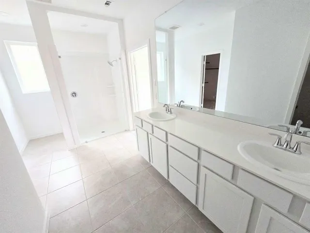 a spacious bathroom with double vanity and a mirror