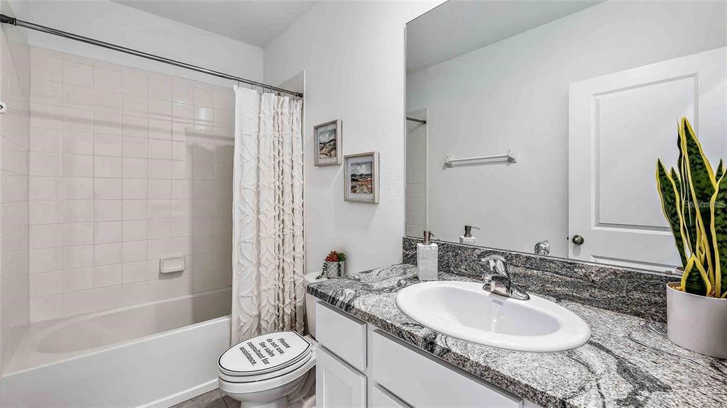 32311 Turtle Grace Loop Wesley Chapel, FL 33545 - Photo 9 of 23 a bathroom with a granite countertop sink toilet a mirror a bathtub and shower