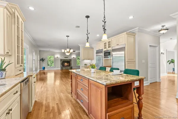 a living room with stainless steel appliances granite countertop furniture wooden floor and a chandelier