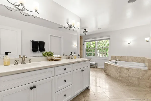 a bathroom with a granite countertop double vanity sink a mirror and a bathtub