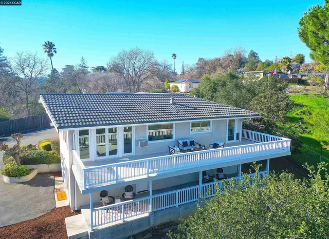an aerial view of a house with balcony and trees in the background