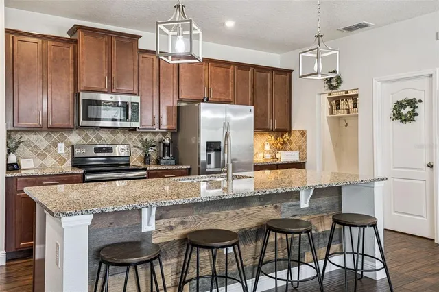 a kitchen with granite countertop a table chairs stove refrigerator and cabinets