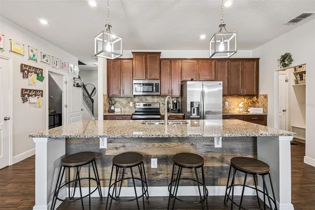a kitchen with stainless steel appliances kitchen island granite countertop a table chairs and a refrigerator