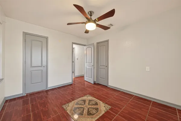 a view of an empty room with wooden floor and a ceiling fan