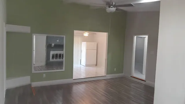 an empty room with wooden floor and a kitchen space