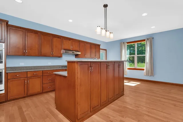 a kitchen with stainless steel appliances granite countertop wooden cabinets a refrigerator and a sink