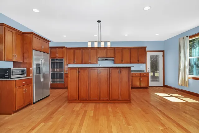 a kitchen with stainless steel appliances wooden cabinets a center island and a refrigerator