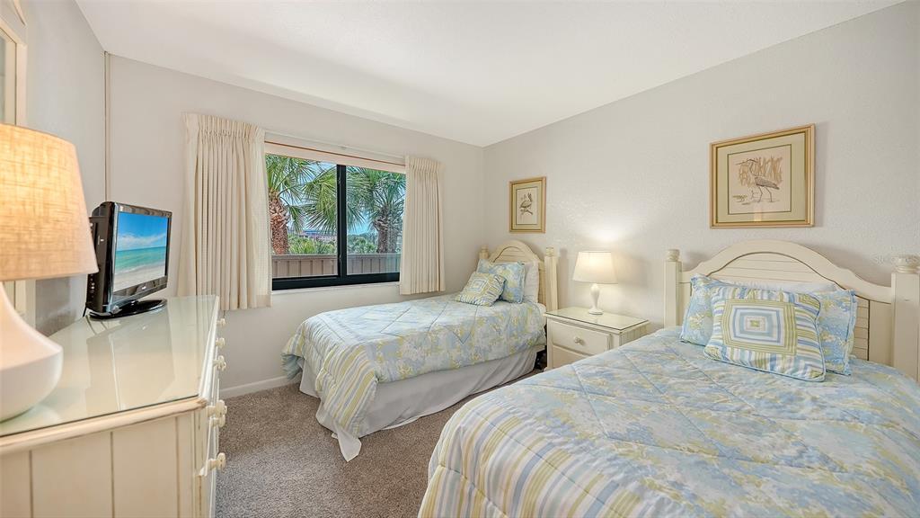 6234 Midnight Pass Road, Unit 307 Sarasota, FL 34242 - Photo 32 of 61 a bedroom with two beds and a flat screen tv