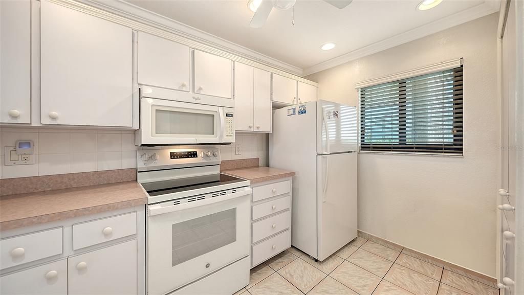 6234 Midnight Pass Road, Unit 307 Sarasota, FL 34242 - Photo 6 of 61 a kitchen with white cabinets and white appliances