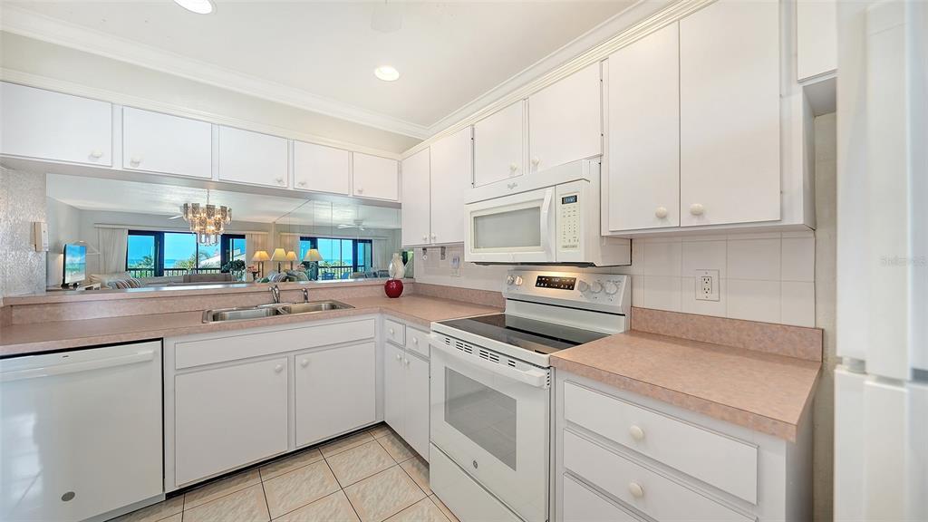 6234 Midnight Pass Road, Unit 307 Sarasota, FL 34242 - Photo 7 of 61 a kitchen with white cabinets appliances and a sink
