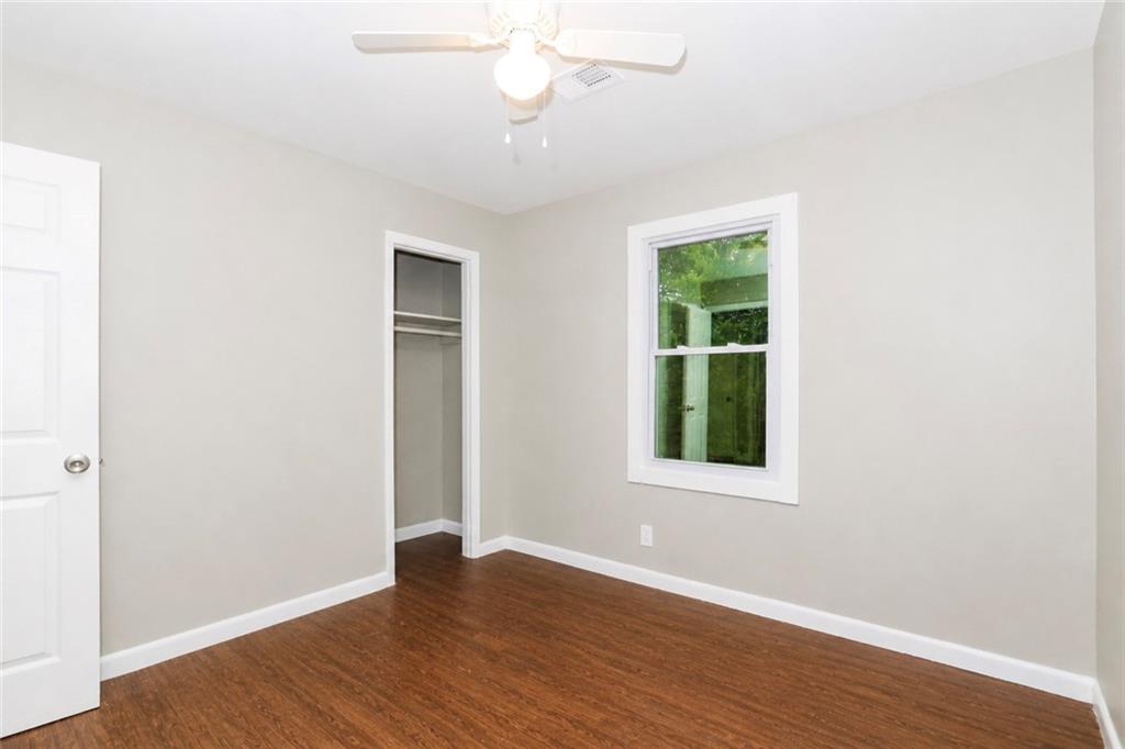 202 Wendan Way Warner Robins, GA 31093 - Photo 6 of 12 an empty room with wooden floor chandelier fan and windows