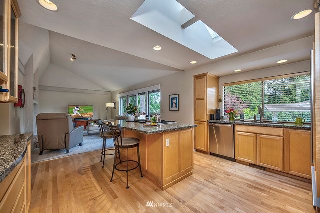 a kitchen with stainless steel appliances granite countertop sink stove refrigerator dining table and chairs