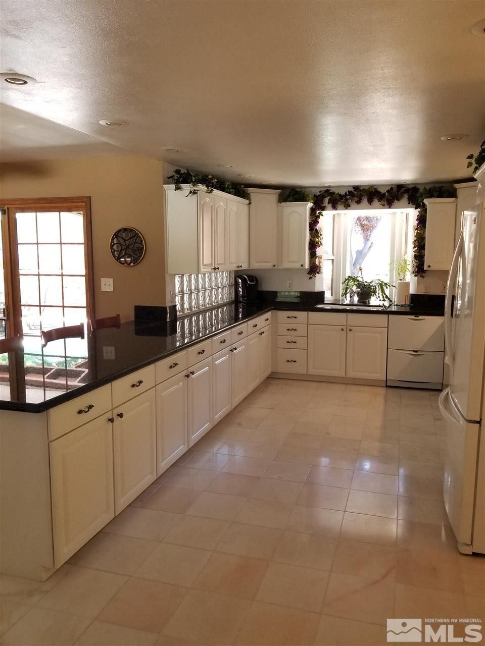 2130 Yuma Lane Reno, NV 89509 - Photo 5 of 25 a large white kitchen with granite countertop a stove a sink a window and white cabinets