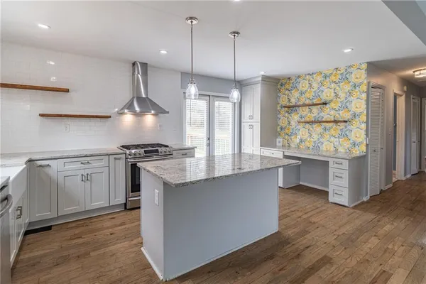 a kitchen with stainless steel appliances granite countertop a stove a sink a center island with wooden floor and cabinets