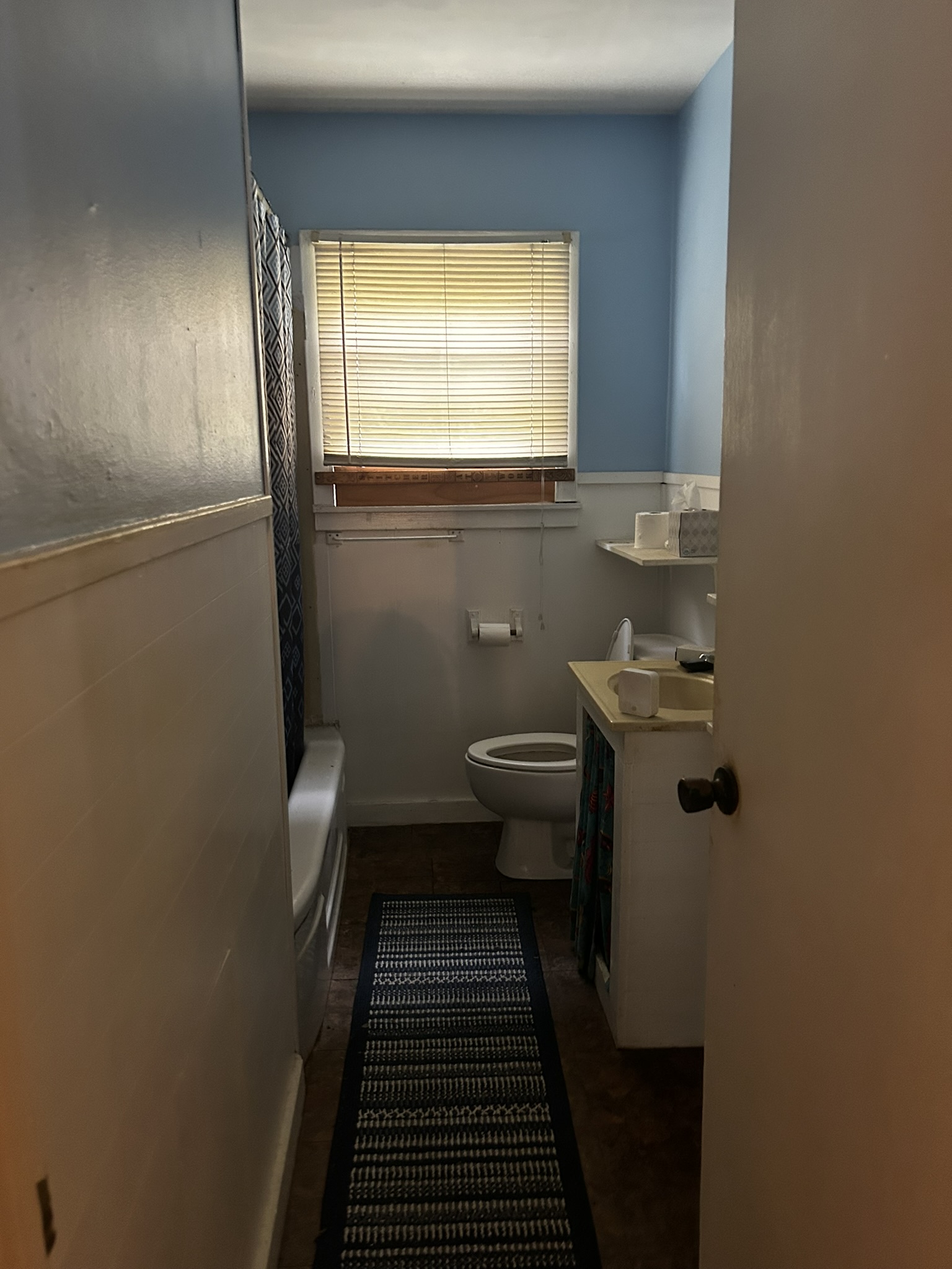 5702 Duval Street Austin, TX 78752 - Photo 27 of 31 Bathroom featuring a window with blinds, a white bathtub, and a toilet
