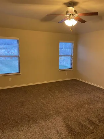 an empty room with a window and a ceiling fan