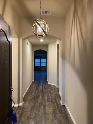 a view of a hallway with wooden floor and chandelier