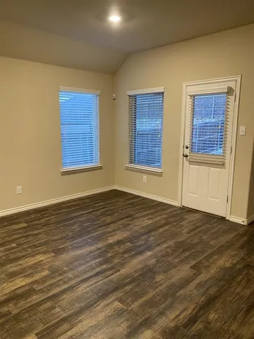 a view of an empty room with wooden floor and windows