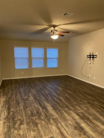 a view of a room with wooden floor and a ceiling fan